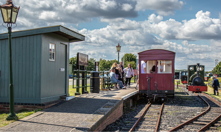 A view of Lakeside station, with passengers sat on the platform seating awaiting "Jurassic" to run around its train.